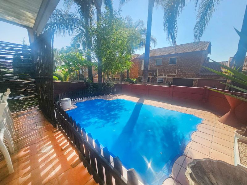 Outdoor pool area featuring a covered swimming pool, tiled patio space, and secure boundary walling in a townhouse setting.