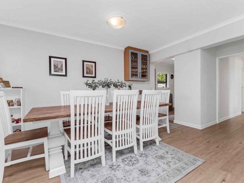 A bright and well-maintained dining area featuring laminate flooring, coved cornicing, and a convenient built-in wall cabinet for storage.