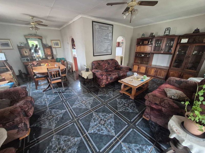 Open plan living and dining area featuring tiled flooring, ceiling fans, and arched doorways leading to adjacent rooms.