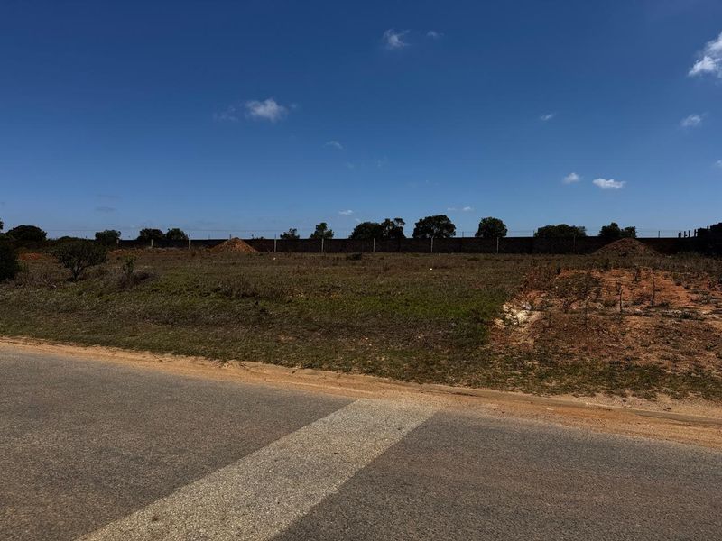 A vacant industrial plot of land featuring perimeter walling and fencing, offering a clear site for future development.