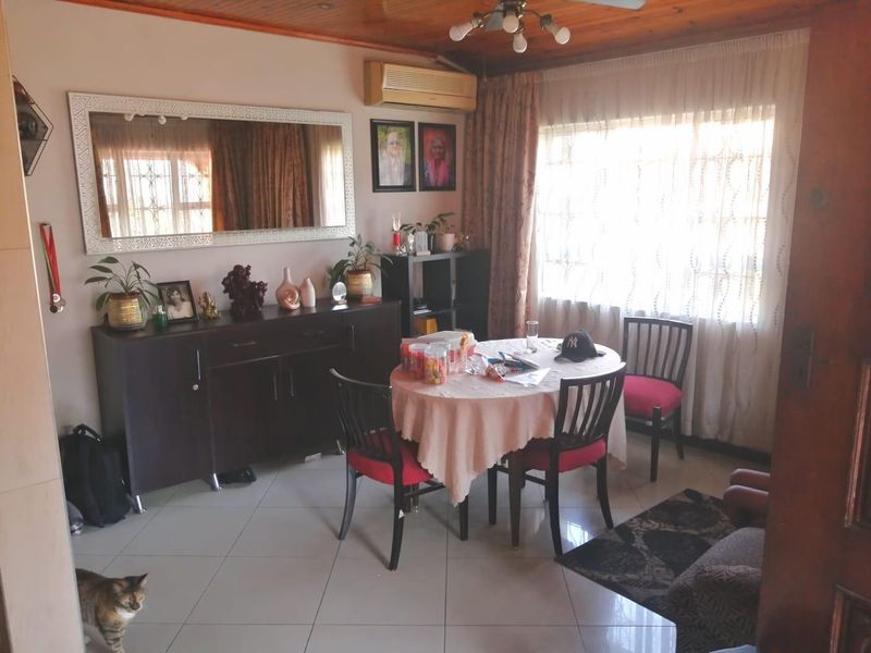 A dining room featuring tiled flooring, a timber-paneled ceiling, and a wall-mounted air conditioning unit, providing a functional space for meals.