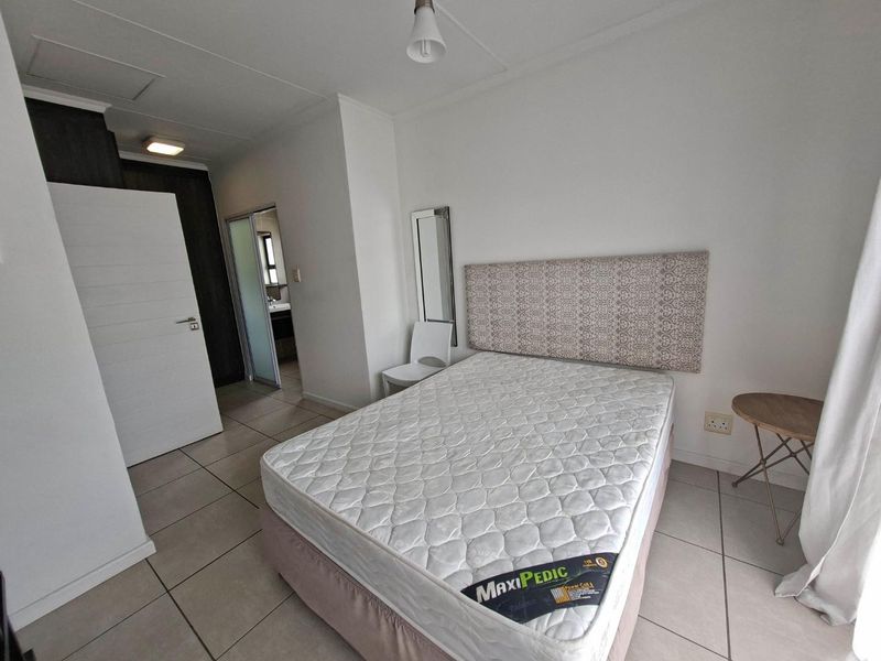 A well-lit bedroom featuring tiled flooring, built-in storage, and direct access to an en-suite bathroom.