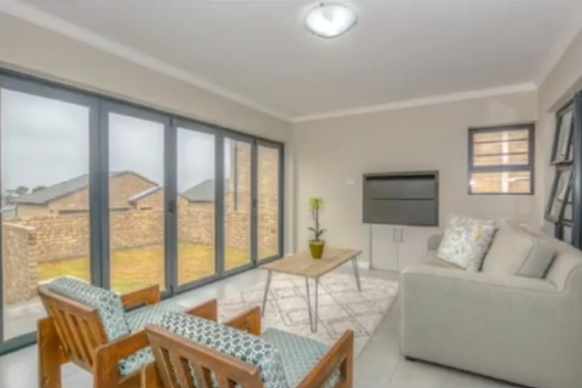 Bright living room featuring large floor-to-ceiling glass sliding doors that open onto a private rear garden area.