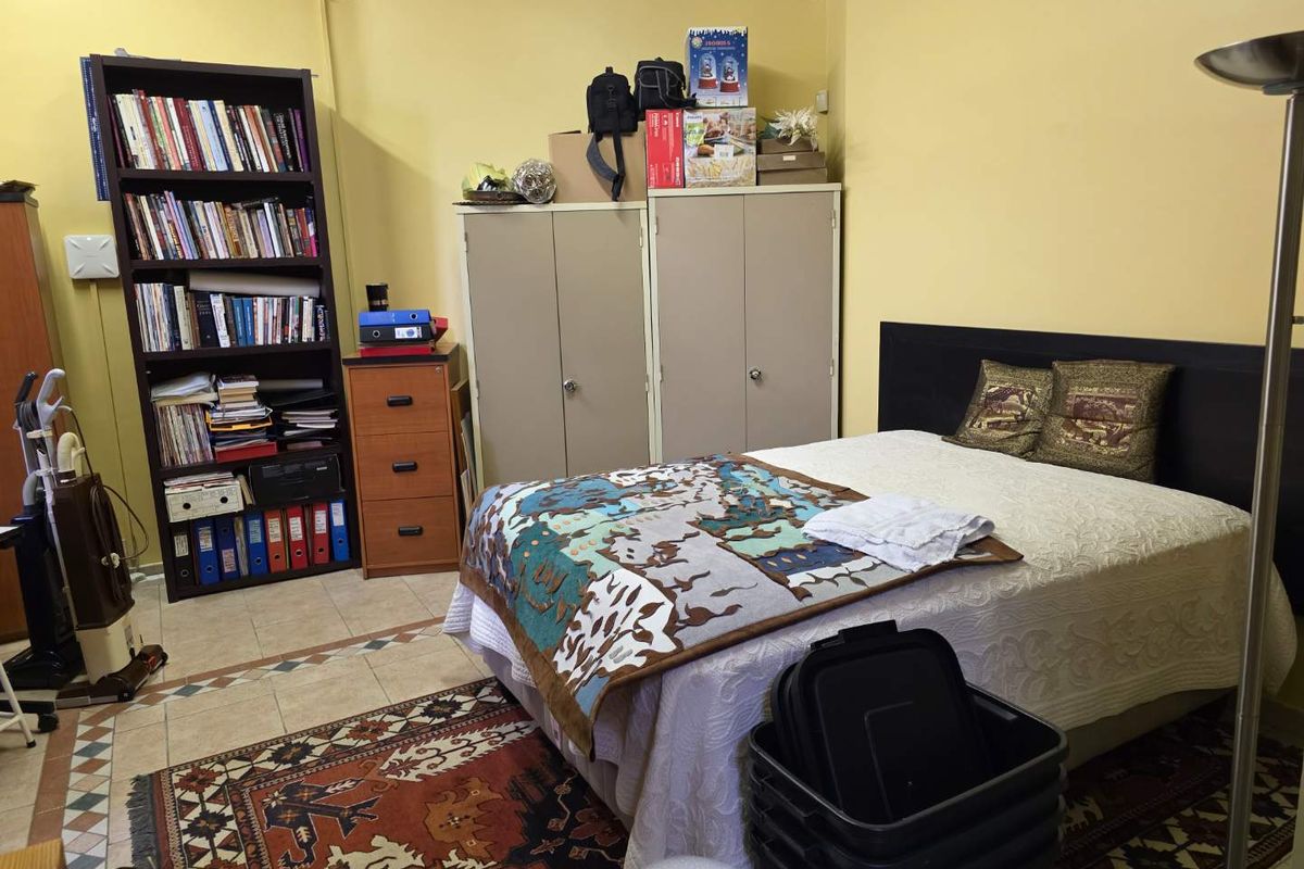 A bedroom featuring tiled flooring and a neutral wall finish, providing a functional space for rest and storage.