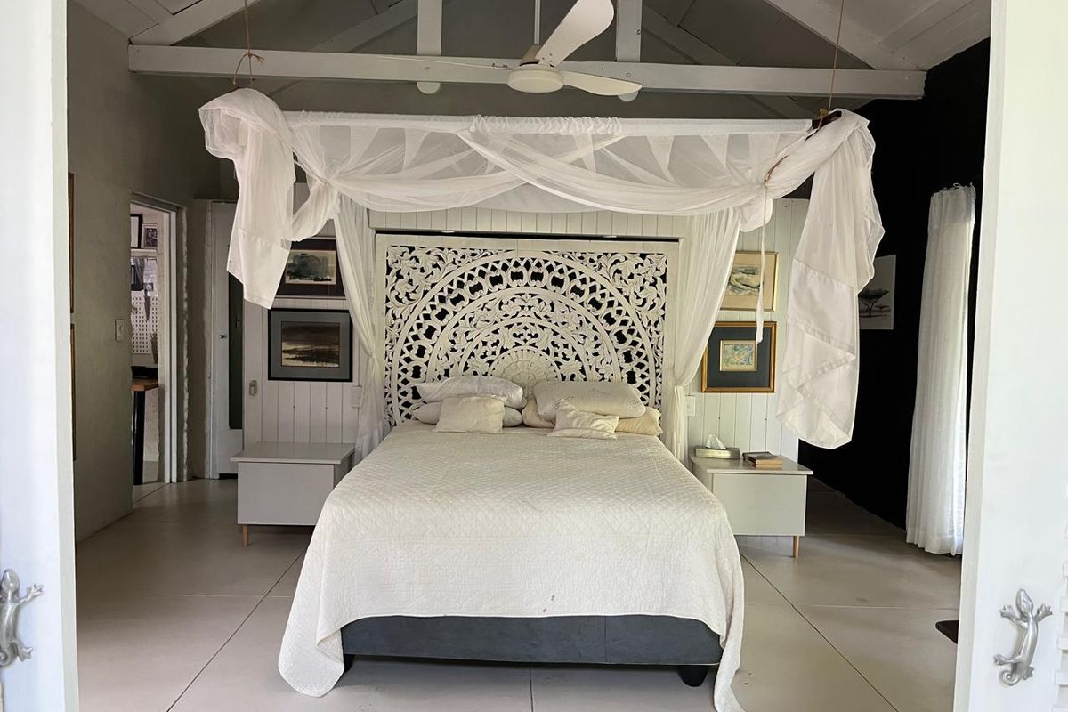 Spacious bedroom featuring a vaulted ceiling with exposed rafters, ceiling fan, and neutral tiled flooring, creating a bright and airy atmosphere.