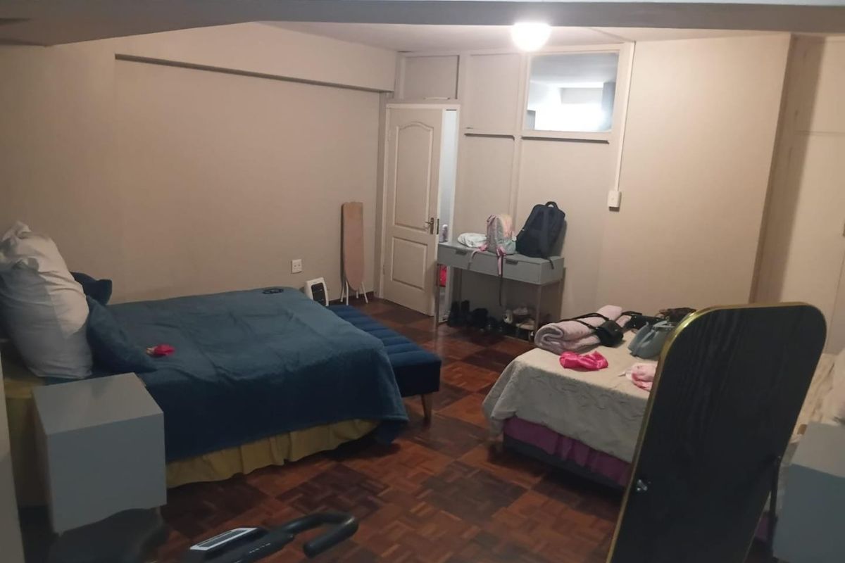 Spacious bedroom featuring classic parquet flooring and built-in storage cupboards, offering a functional layout with potential for modern cosmetic updates.