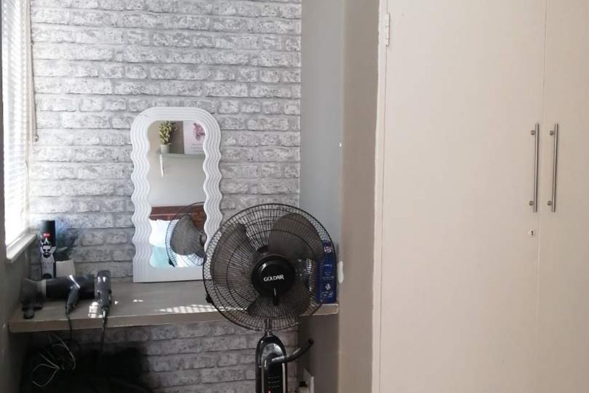Bedroom featuring a built-in wardrobe, split-system air conditioning unit, and a built-in vanity shelf against a decorative faux brick feature wall.
