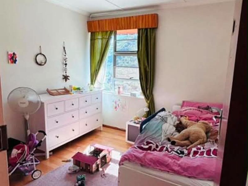 A functional bedroom featuring laminate flooring and a window with natural light, providing a comfortable space for rest.