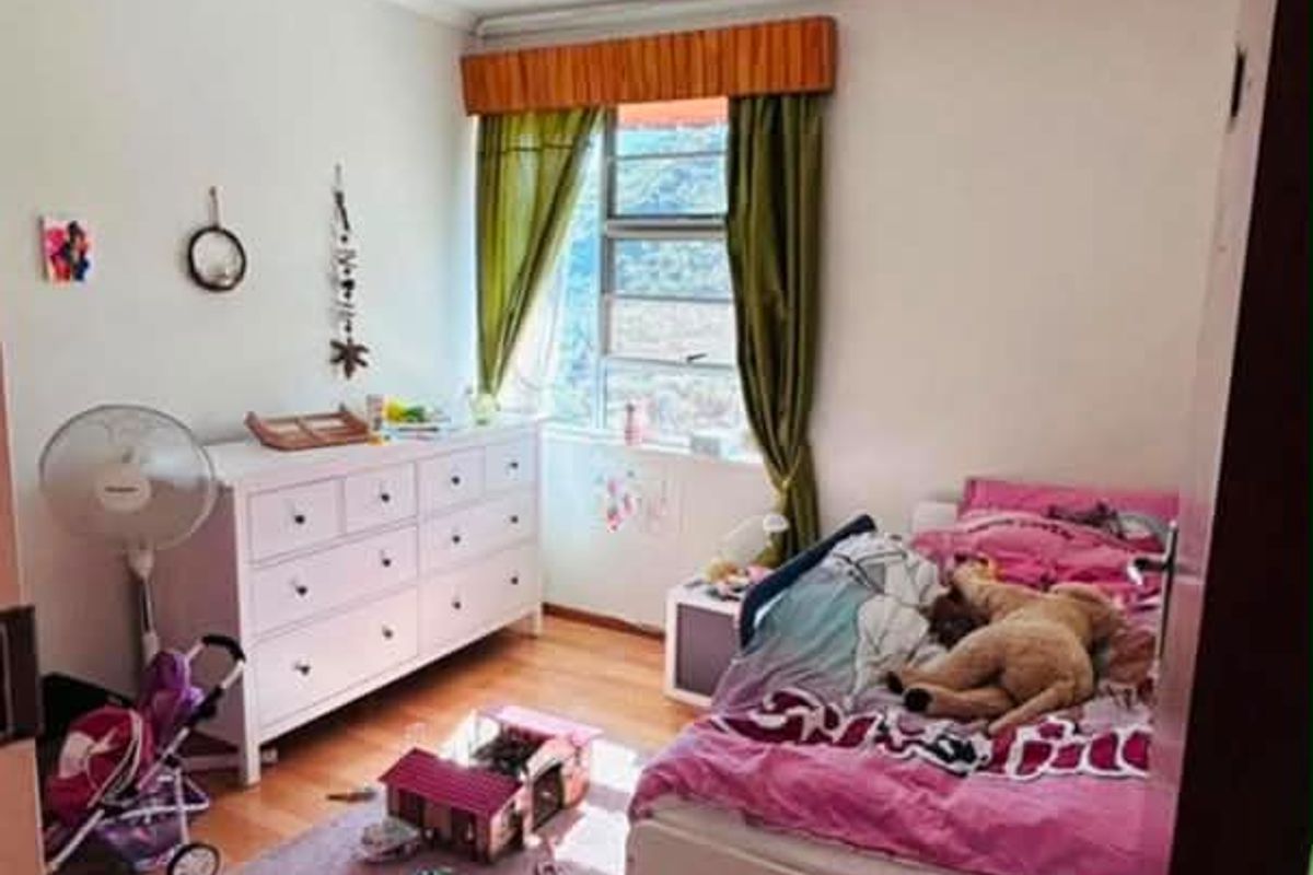A functional bedroom featuring laminate flooring and a window with natural light, providing a comfortable space for rest.