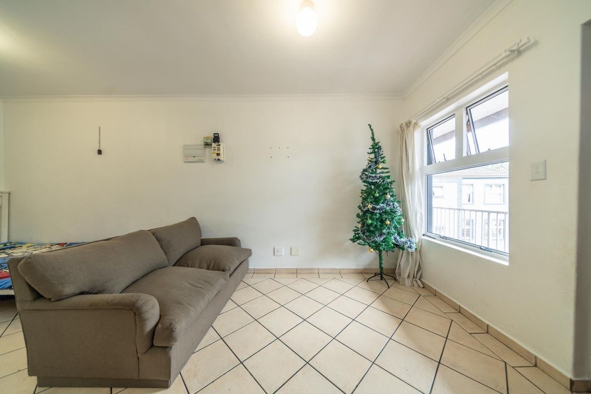 A living room area featuring tiled flooring and an aluminium window, providing a functional space with potential for modern updates.