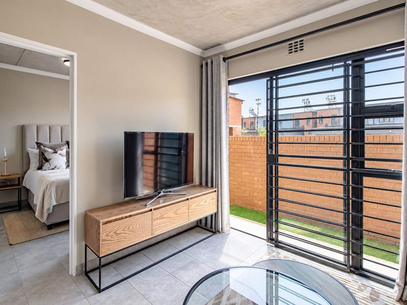 Modern living room featuring tiled floors, a sliding glass door with security gate, and direct access to an outdoor area.