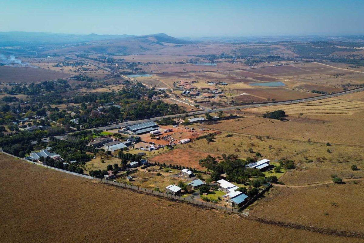 Aerial view of a large agricultural property featuring multiple structures, expansive open land, and surrounding rural landscape.