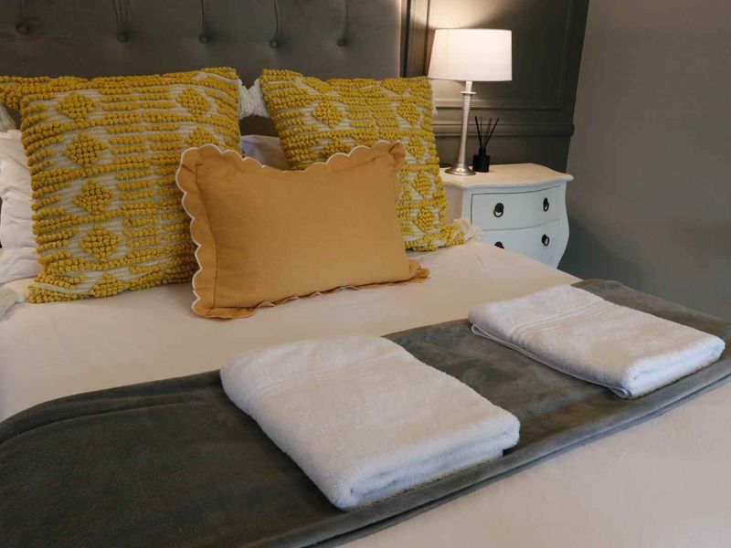 A well-appointed bedroom featuring a grey upholstered headboard and decorative wall paneling, creating a comfortable and stylish sleeping space.