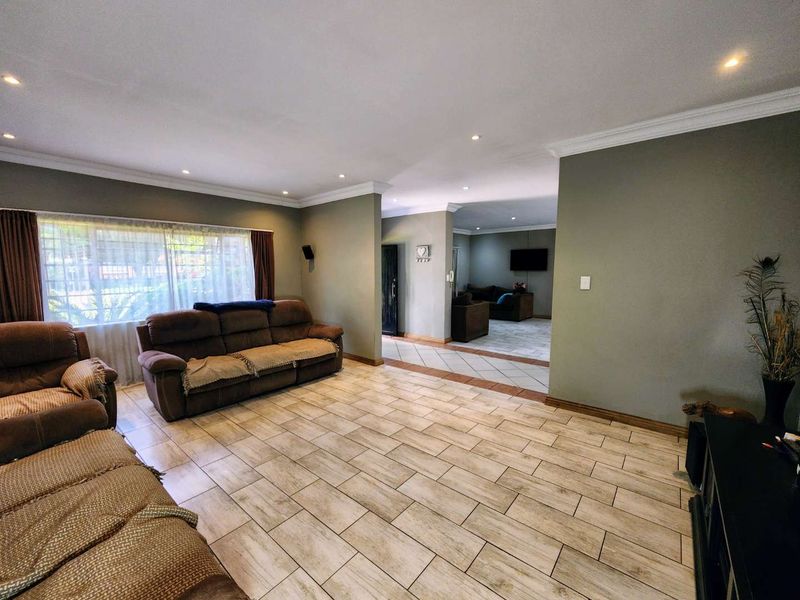 Spacious living area featuring neutral wall tones, ceramic tiled flooring, and recessed downlighting, offering a comfortable and versatile space for relaxation.
