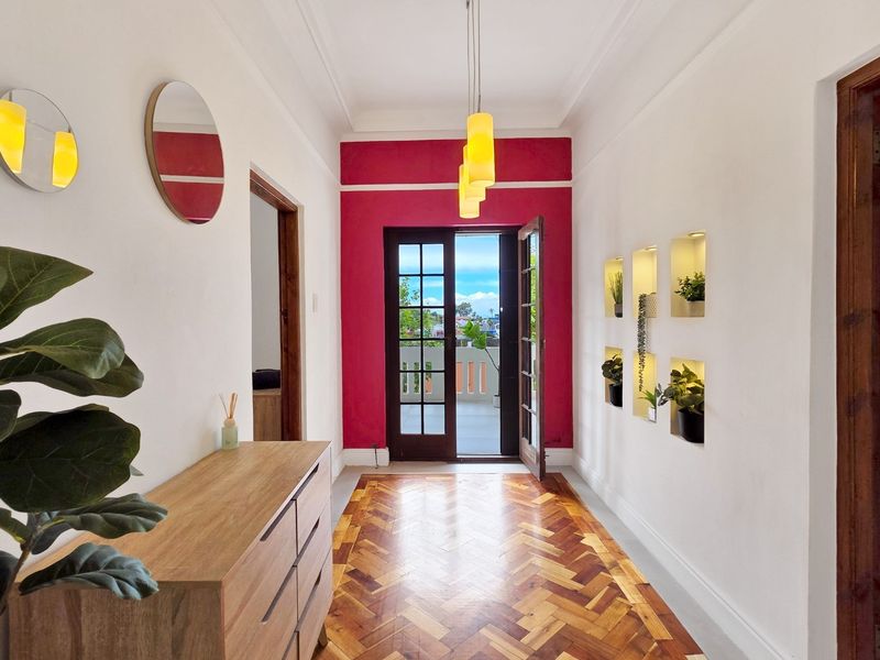 Welcoming entrance hall featuring classic herringbone parquet flooring, decorative recessed wall niches, and elegant french doors leading to an outdoor balcony area.