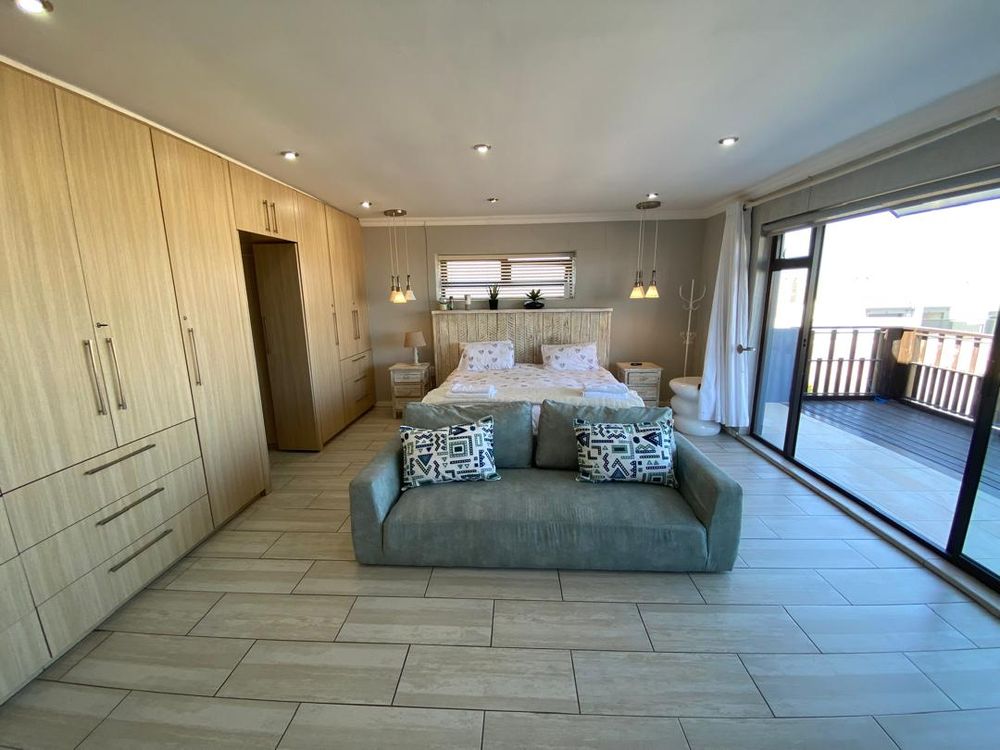 First-floor main bedroom with built-in cupboards and en-suite bathroom. It also has a balcony with distant sea views