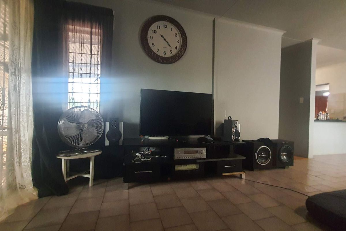 A living room area featuring tiled flooring and a view through to the kitchen space.