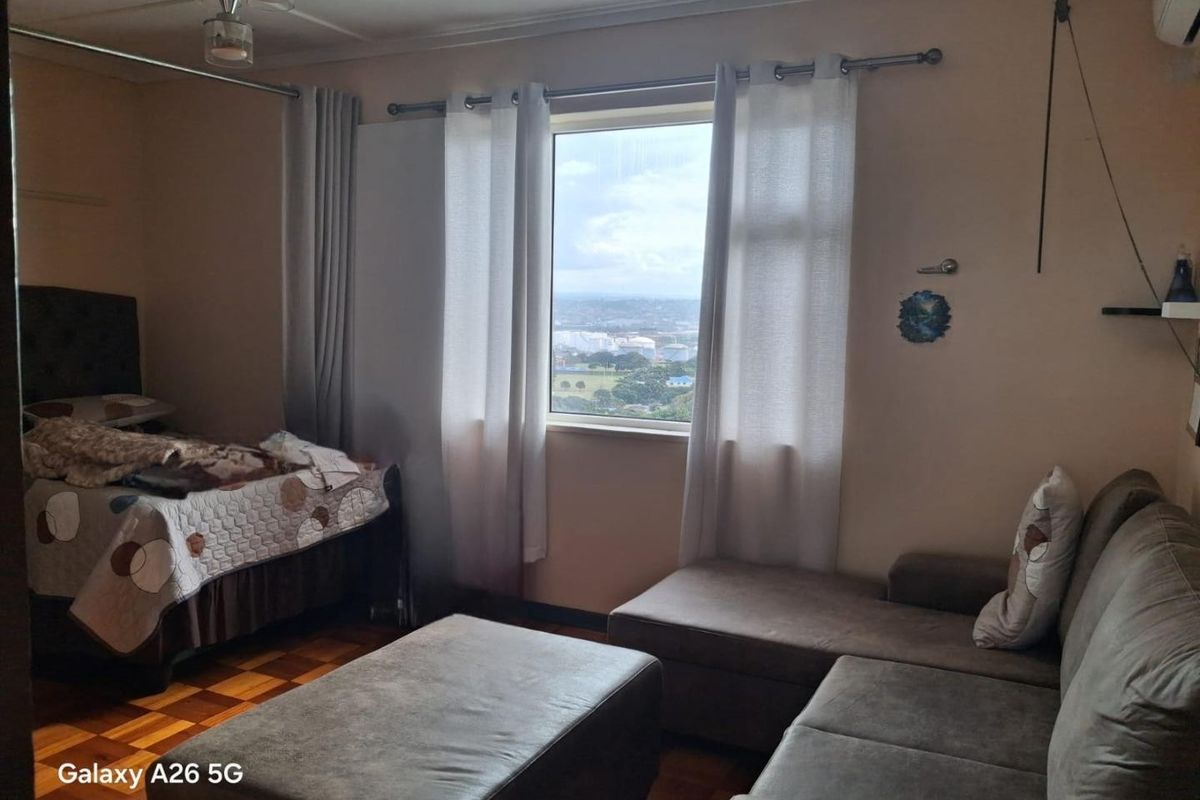A bedroom featuring parquet flooring and a window with views, requiring cosmetic updates to improve the overall aesthetic and condition.