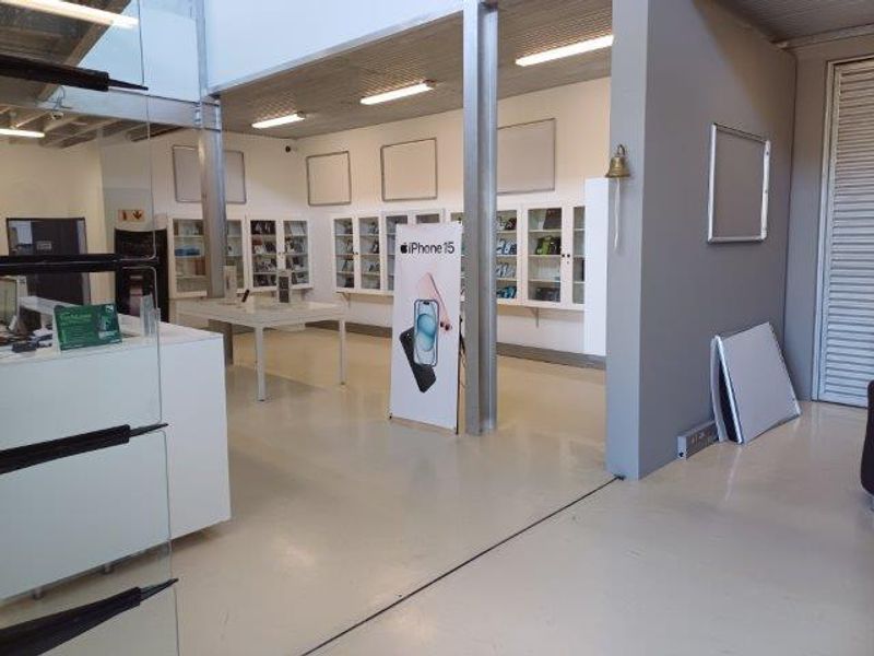 Open-plan office or retail space featuring built-in display cabinetry, industrial steel columns, and durable epoxy flooring with modern lighting.