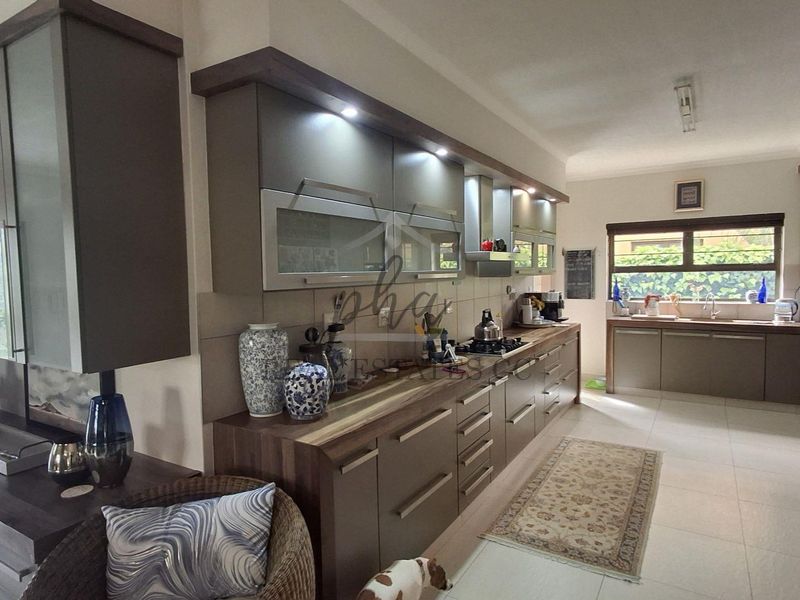 Modern kitchen featuring sleek cabinetry, gas hob, extractor fan, and tiled flooring with ample counter space and integrated storage solutions.