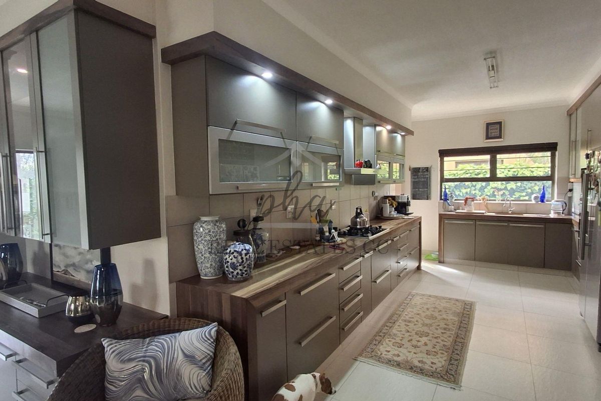 Modern kitchen featuring sleek cabinetry, gas hob, extractor fan, and tiled flooring with ample counter space and integrated storage solutions.