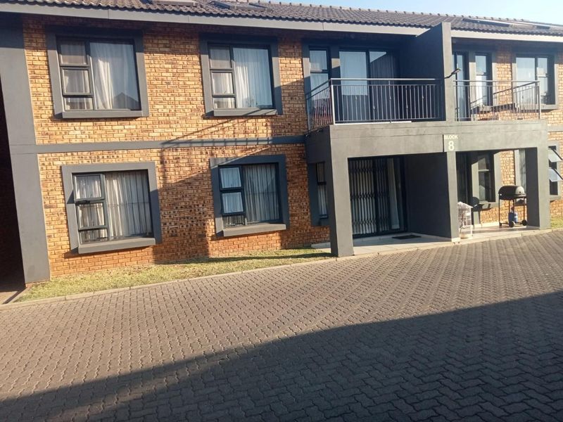 Front elevation of a two-story townhouse block featuring face brick construction, aluminium window frames, and a private balcony with metal railings.