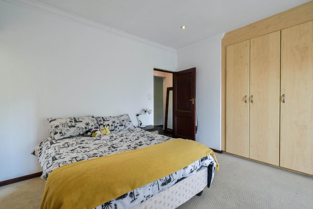 A well-maintained bedroom featuring neutral carpeting, built-in light wood cabinetry, and recessed ceiling lighting.