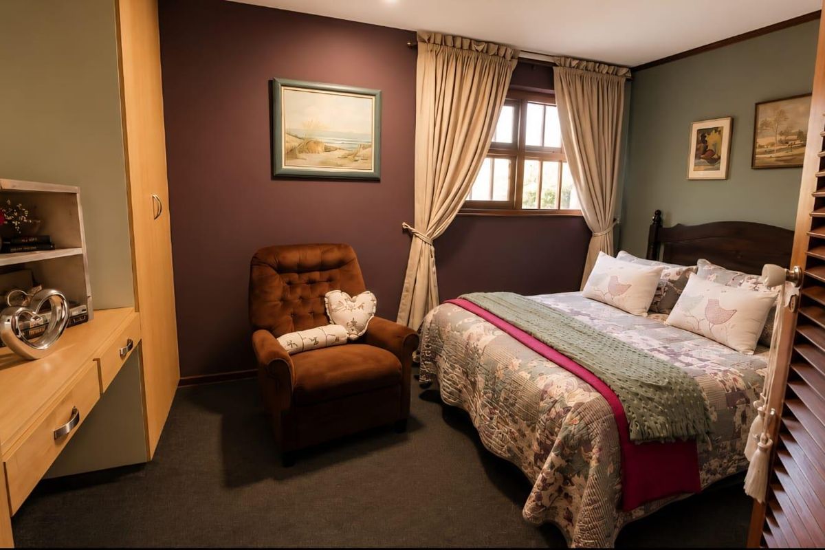 A cozy bedroom featuring built-in cabinetry, a dedicated desk area, and timber-framed windows, offering a functional and comfortable living space.