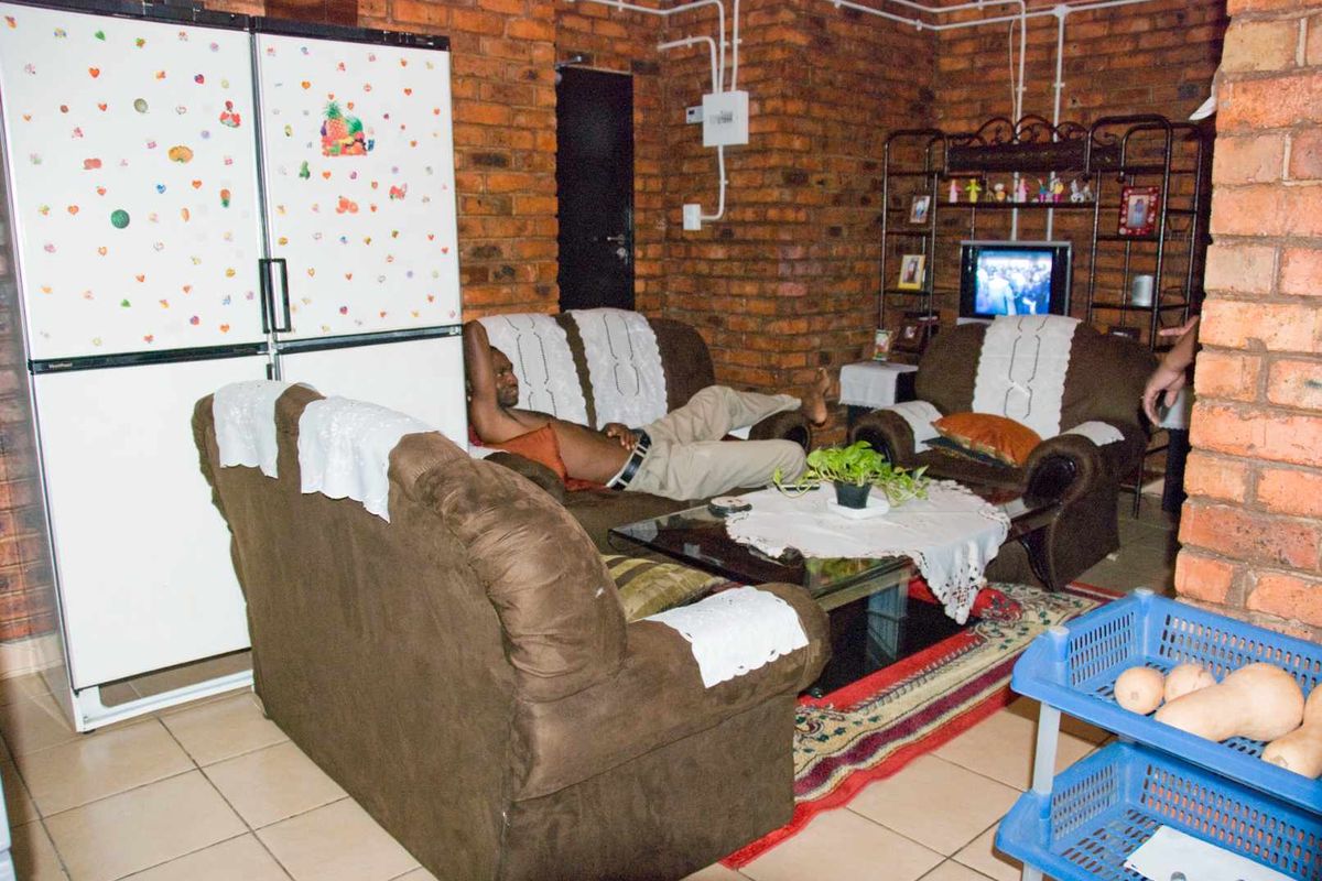 Living area featuring exposed brick walls and ceramic tile flooring, with visible surface-mounted electrical conduit and wiring throughout the space.