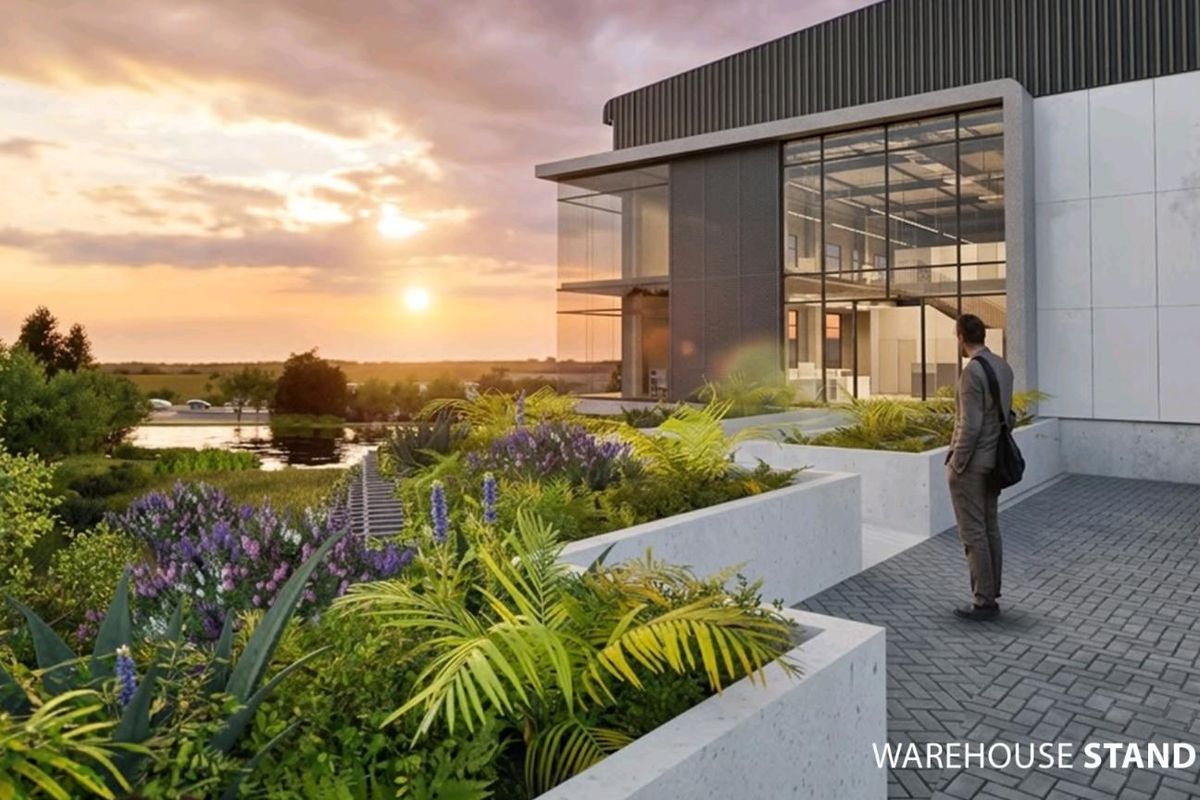 Architectural rendering of a modern industrial warehouse facility featuring glass facade, concrete planters, and paved exterior area at sunset.