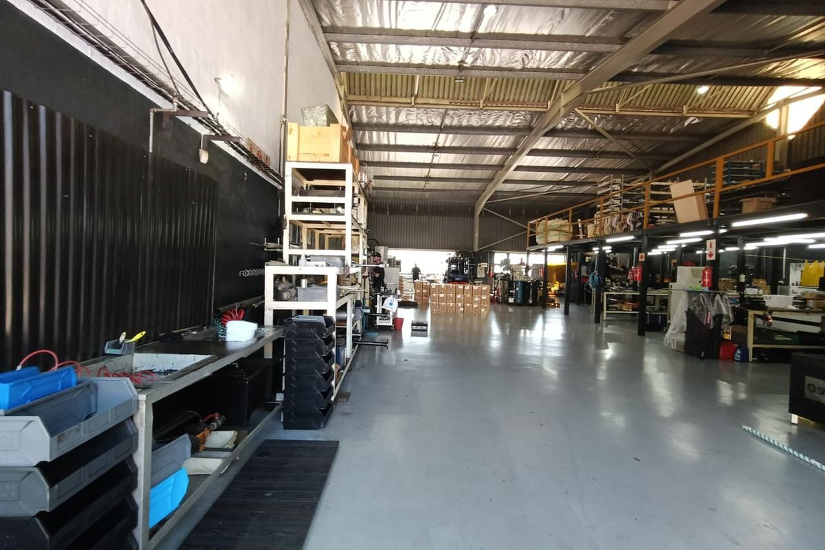 Spacious industrial warehouse featuring high ceilings with exposed steel trusses, a mezzanine level, and durable epoxy-coated concrete flooring suitable for various commercial operations.
