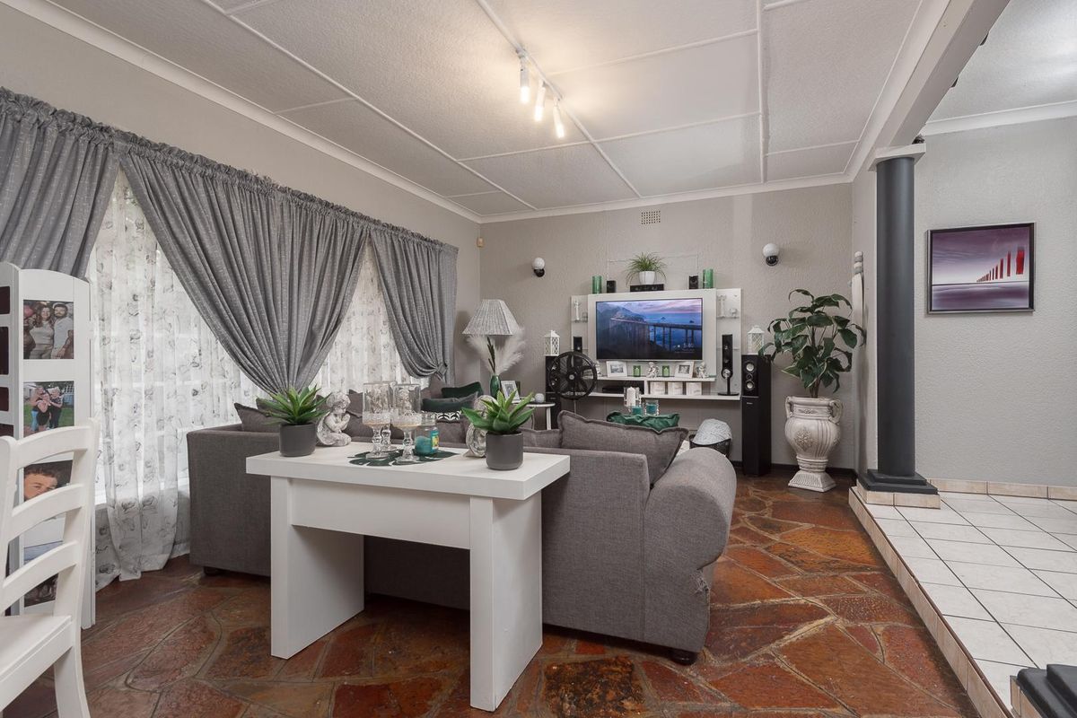 A spacious living room featuring unique natural stone flooring, a decorative column, and a built-in media wall unit.