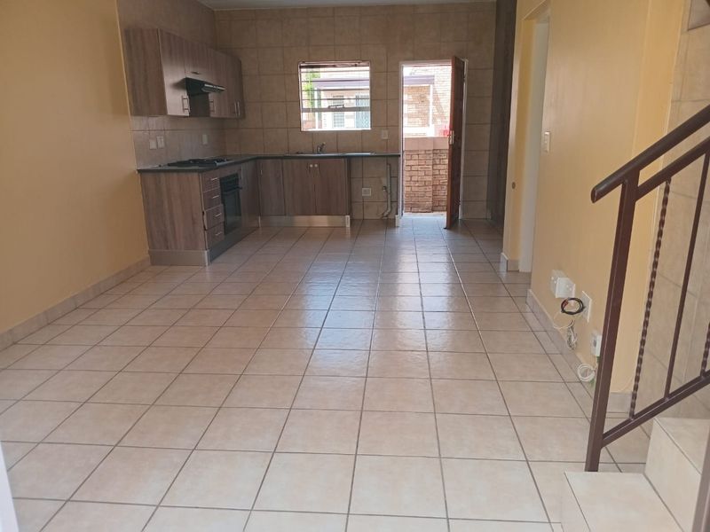 Open plan kitchen and living area featuring tiled flooring, built-in cabinetry with integrated appliances, and direct access to an outdoor space.