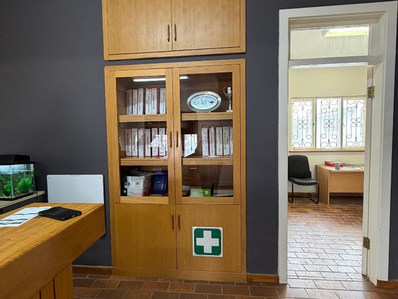 Office space featuring built-in wooden cabinetry, tiled flooring, and a doorway leading to an adjacent room with security-barred windows.