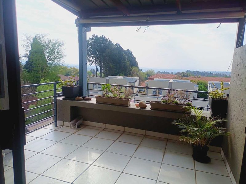 A covered balcony featuring tiled flooring, a metal balustrade, and a concrete ledge, offering an elevated view of the surrounding residential area.