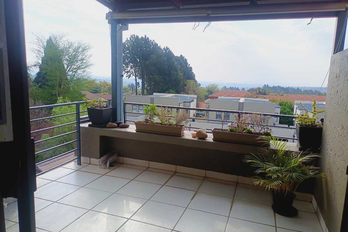 A covered balcony featuring tiled flooring, a metal balustrade, and a concrete ledge, offering an elevated view of the surrounding residential area.