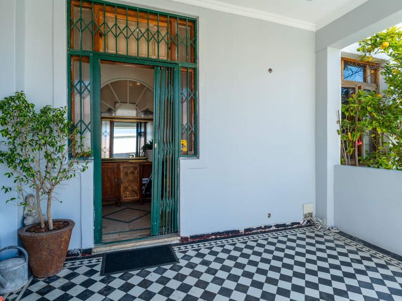 A covered patio area featuring classic black and white checkered tile flooring and a secure metal entrance gate.