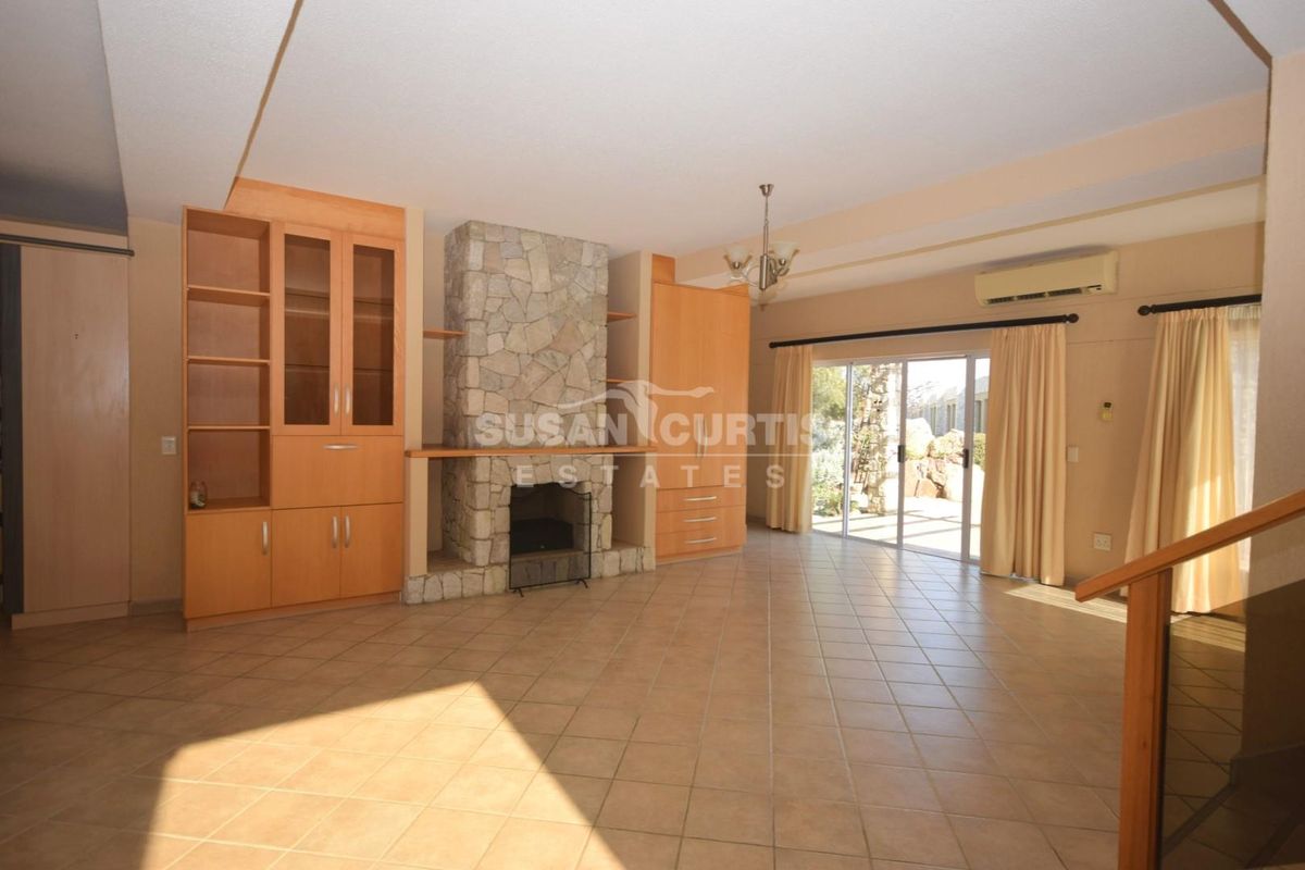 Spacious living room featuring a stone fireplace, built-in cabinetry, tiled flooring, and sliding glass doors leading to the outdoor area.