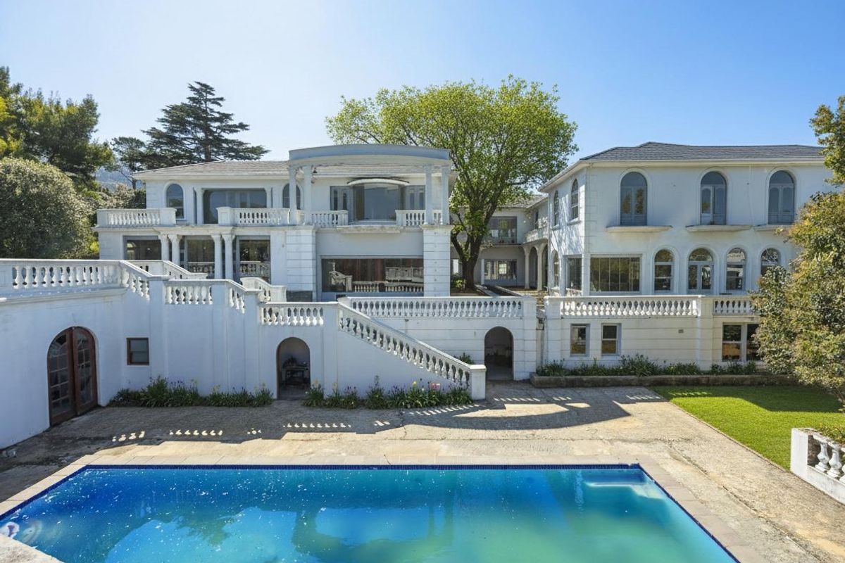 Expansive rear elevation of a multi-story residence featuring a swimming pool, stone balustrades, and a large terrace area.