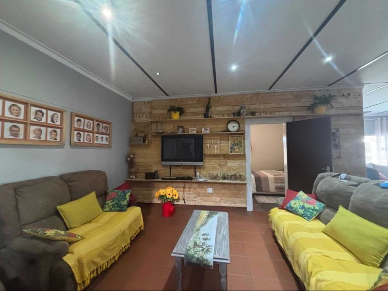 A living room featuring tiled flooring, recessed downlights, and a timber panel feature wall with integrated shelving.
