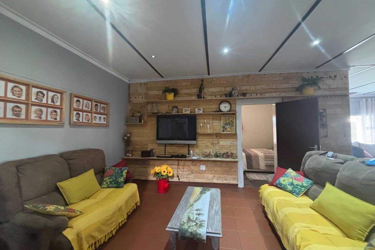 A living room featuring tiled flooring, recessed downlights, and a timber panel feature wall with integrated shelving.