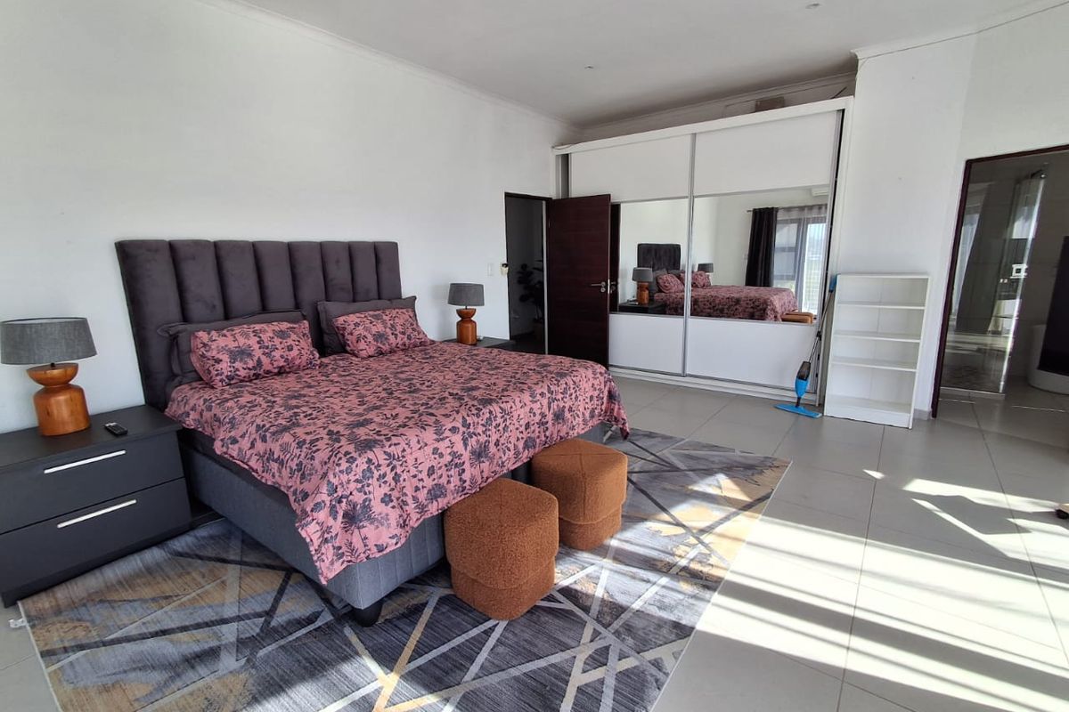 Spacious bedroom featuring large format floor tiles, recessed lighting, and a substantial built-in wardrobe with mirrored sliding doors.