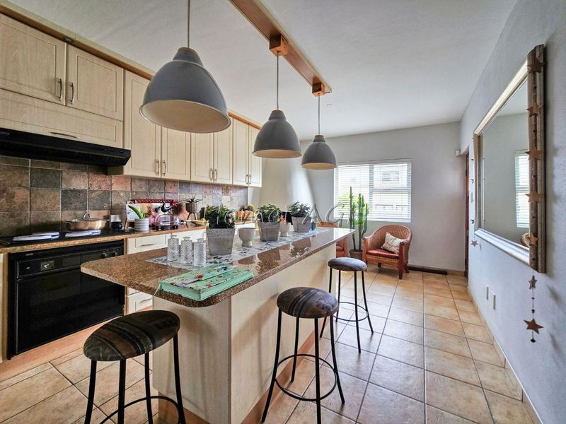 A functional kitchen featuring granite countertops, tiled backsplash, ample cabinetry, and a breakfast bar with pendant lighting.