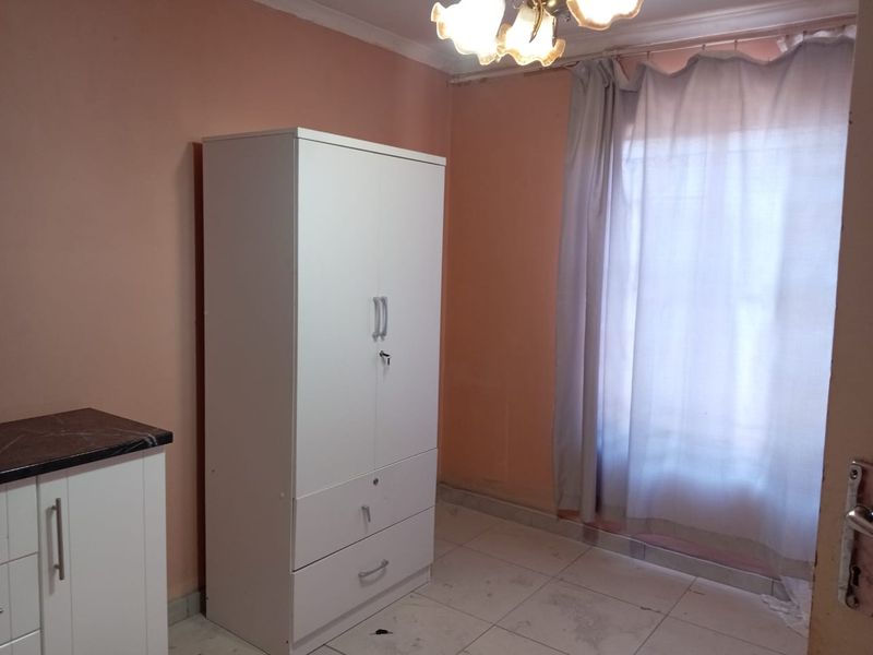 A bedroom featuring tiled flooring and ceiling cornice, currently requiring cosmetic updates to the wall finishes and flooring to improve its overall condition.