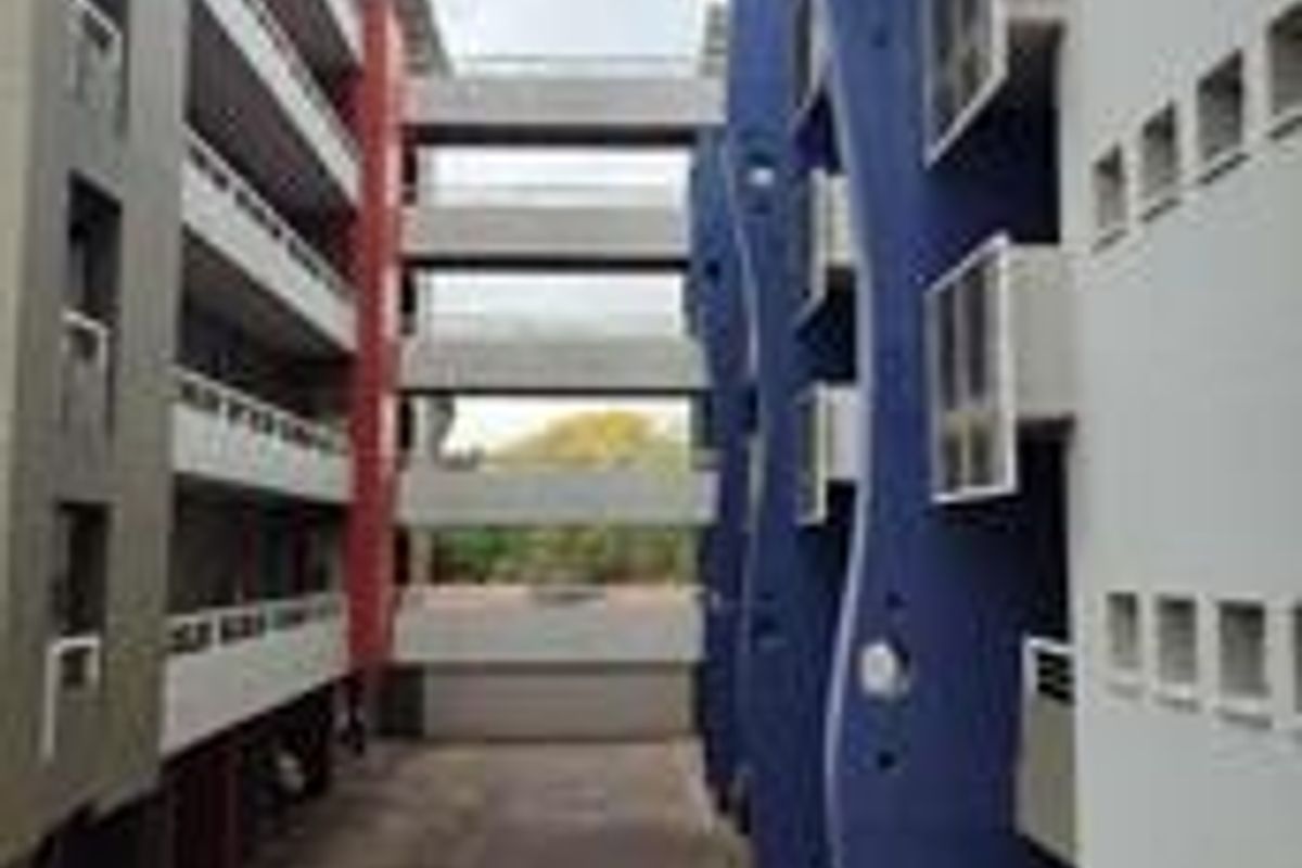 Exterior view of an apartment complex featuring multi-level walkways connecting two building blocks with distinct architectural facade elements.