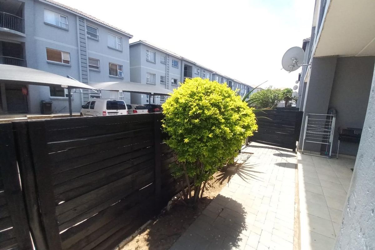 A paved rear patio area featuring a timber privacy fence and direct access to the townhouse exterior.