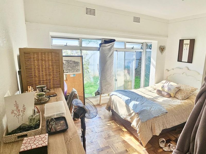 A bedroom featuring parquet flooring, built-in storage, and large sliding glass doors that provide natural light and access to the outdoor area.