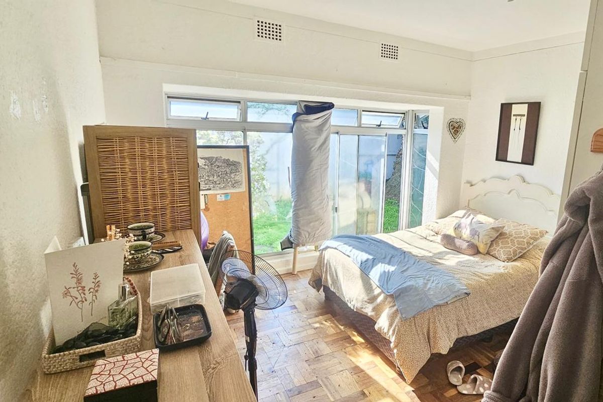 A bedroom featuring parquet flooring, built-in storage, and large sliding glass doors that provide natural light and access to the outdoor area.