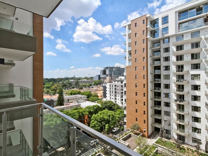 Elevated urban view from a modern penthouse balcony, showcasing surrounding high-rise architecture and landscaped greenery.