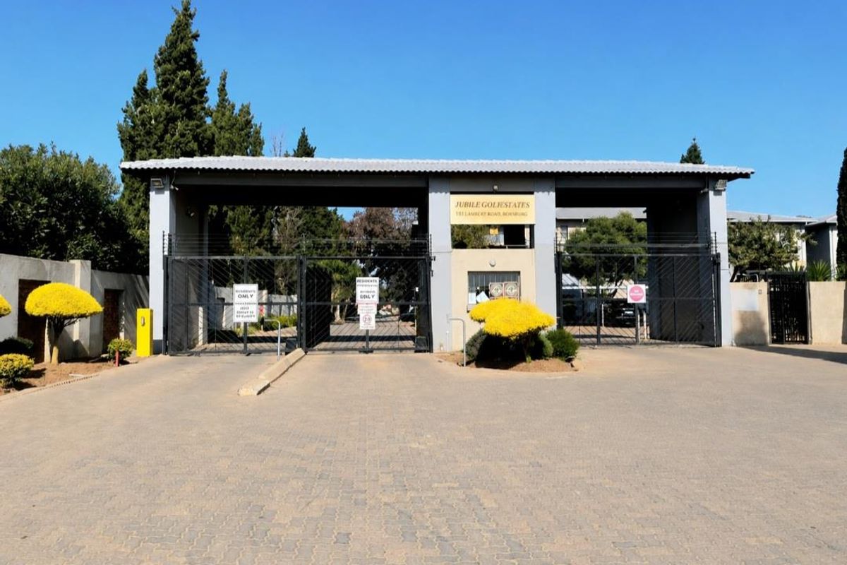 The main entrance to Jubilee Goli Estates, featuring a secure gated access point with electric fencing and a paved driveway.